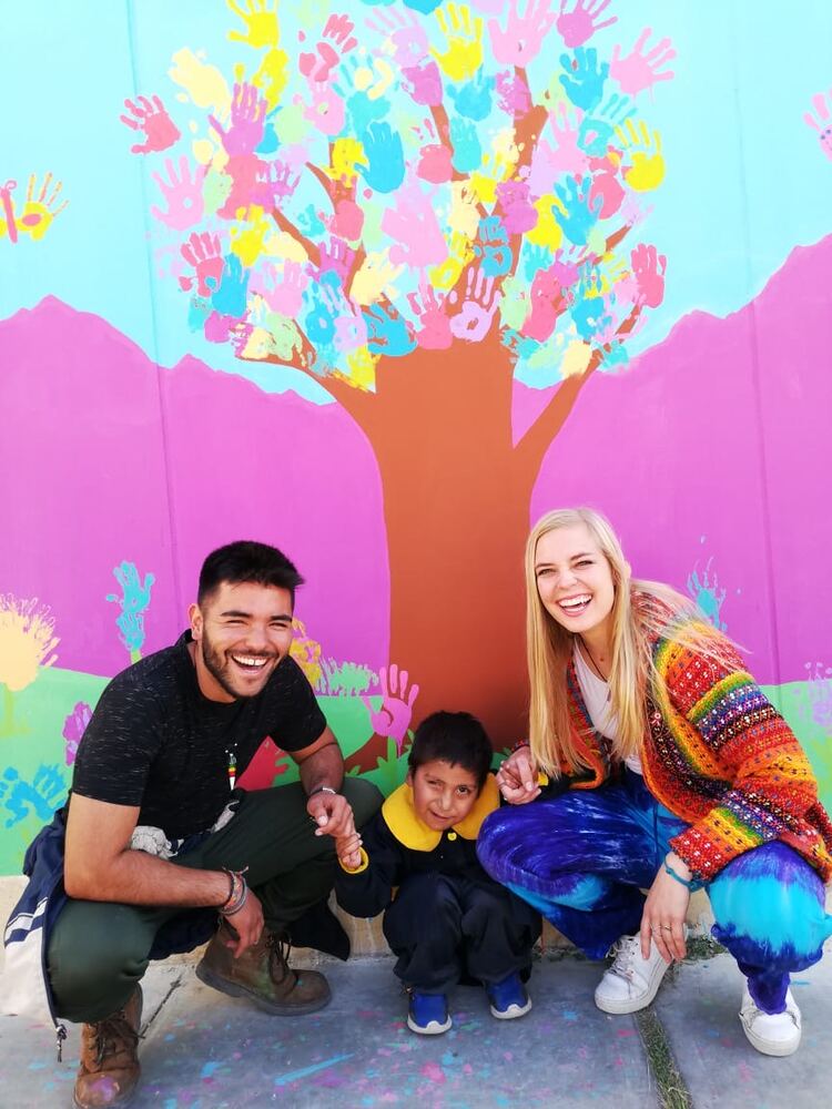 Volunteers and a child in front of a mural they painted together